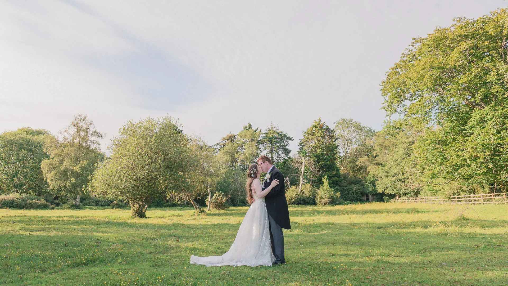 Bride and groom kiss in a New Forest meadow outside Carey's Manor