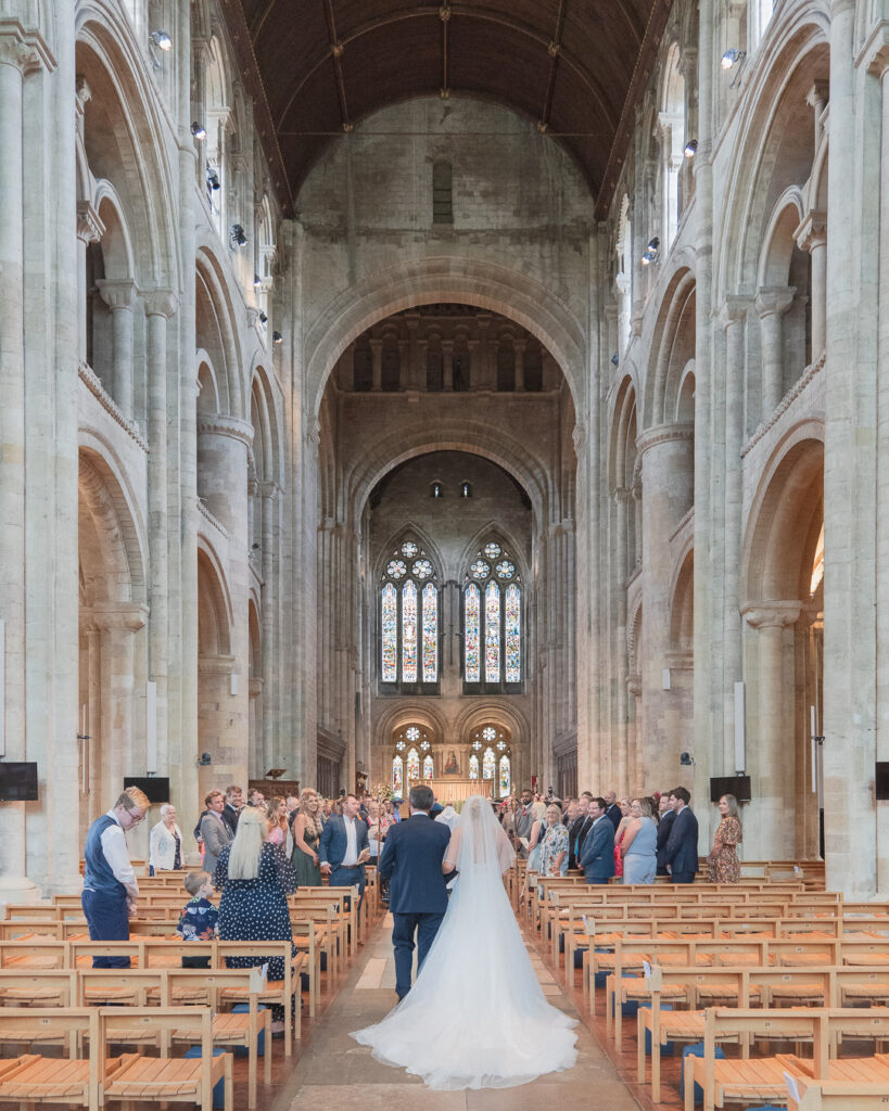 Bride and her father walk up the aisle in Romsey Abbey