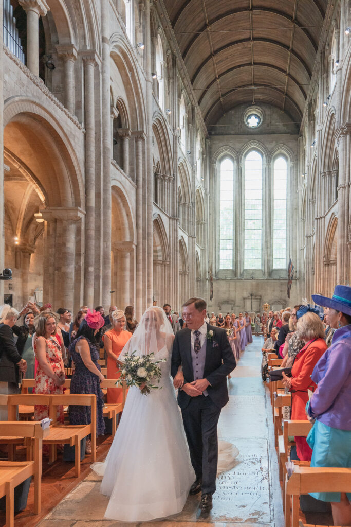 Bride and her father walk up the aisle in Romsey Abbey