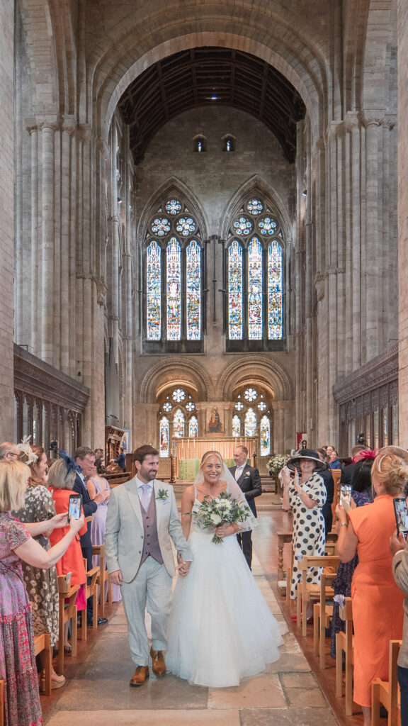 Bride and groom walk down the aisle in Romsey Abbey
