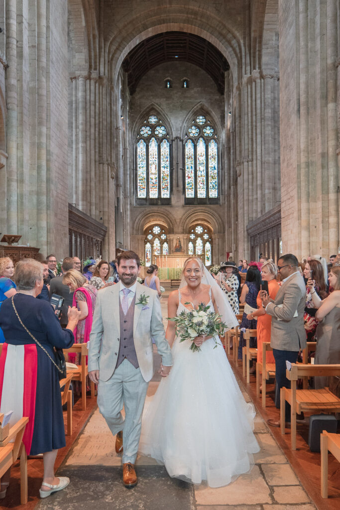 Bride and groom walk down the aisle in Romsey Abbey